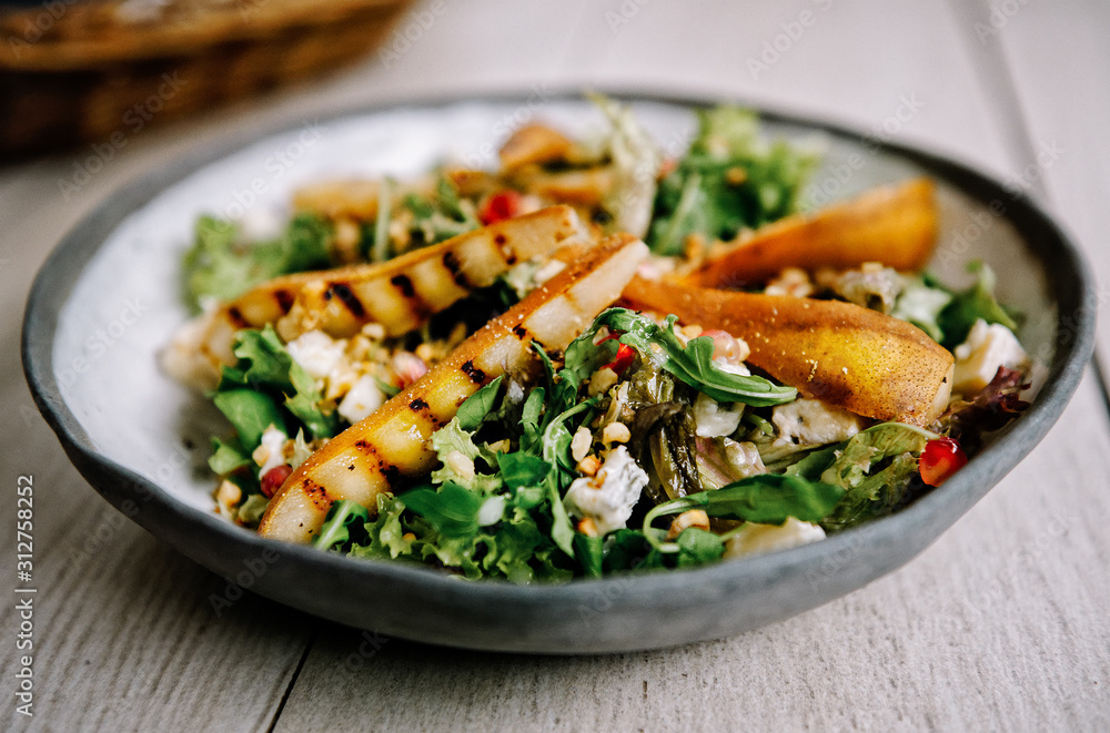 Healthy vegetarian dinner or lunch.  Salad with caramelized grilled pear, walnuts, blue cheese and pomegranate seeds.