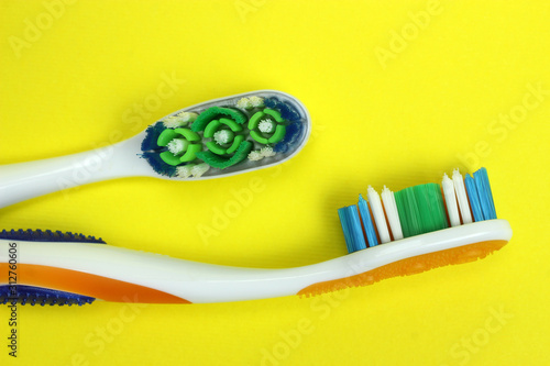 Two toothbrushes on a yellow background