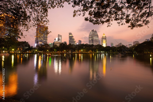 Landscape of the tall building with water reflaction at Lumpini park , Bangkok , Thailand. The Building in capital of Thailand with sunset at Lumpini park.