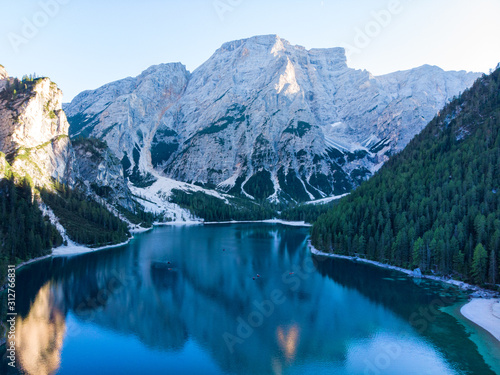 Braies Lake in Dolomites mountains forest trail in background, Sudtirol, Italy. Lake Braies is also known as Lago di Braies. The lake is surrounded by forest which are famous for scenic hiking trails.