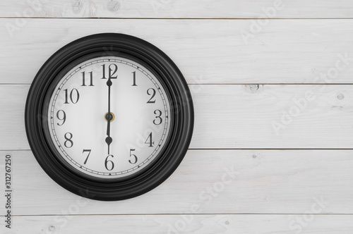 wall round clock black and white with number and clockwise on six o'clock straight or 6 am pm for working time start or go to school and morning wake up on white wood wall or top view table with space