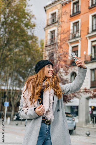 Beautiful caucasian girl makes a selfie in the street on a cold winter day