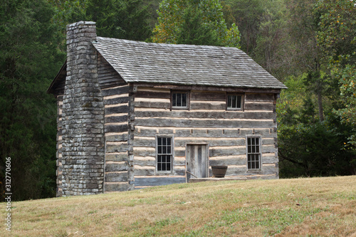 Tableau sur toile Log Cabin in a field of grass