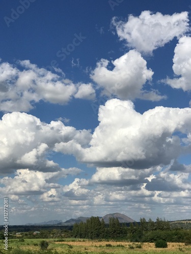 blue sky and white clouds with green fields