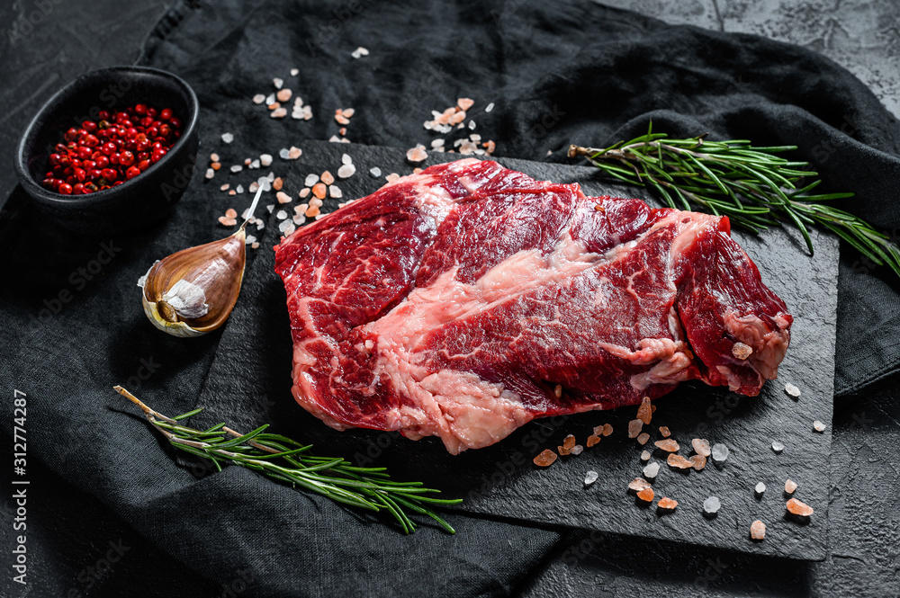 Raw beef steak on a chopping Board. Organic farm meat. Black background