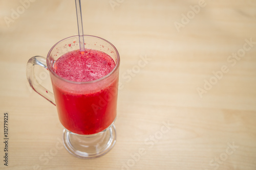 A glass full of blueberry juice placed on a wooden surface.