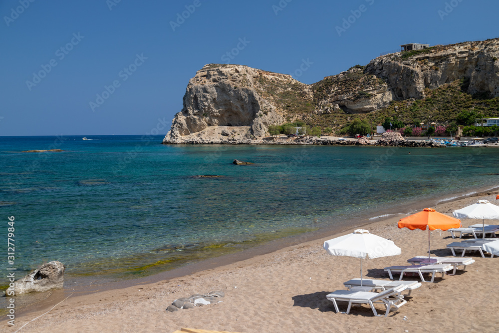 Stegna beach on Greek island Rhodes with sand, sunshades and boats in the background