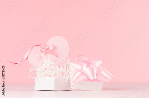 Valentine days decor and gift in soft light pastel pink color - heart, gift box with ribbon and bow on white wood table, closeup. photo