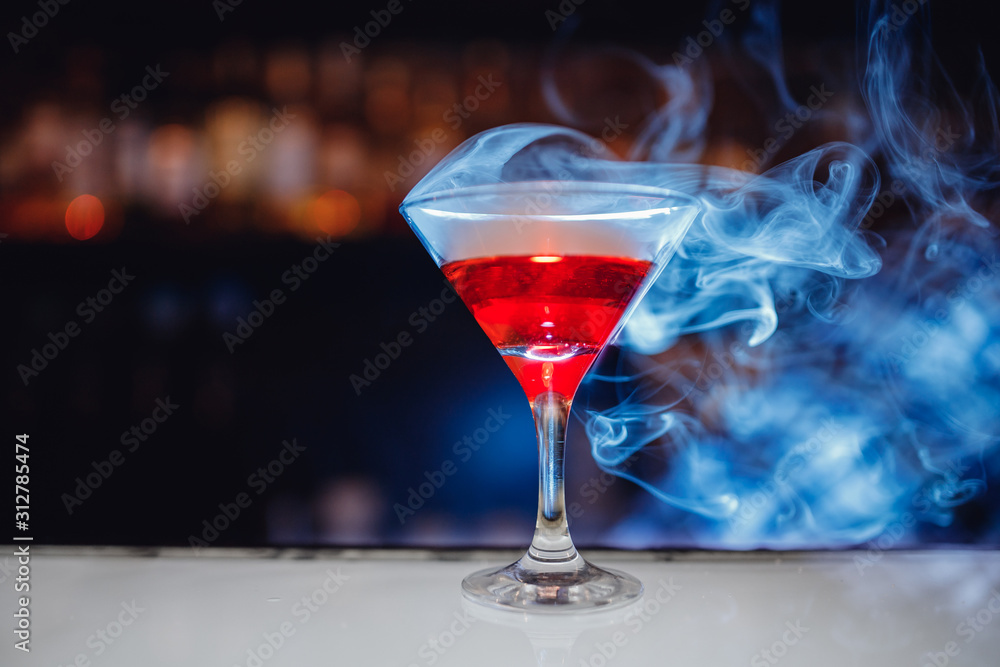 Red cocktail in martini glass with smoke, bartender drinks concept
