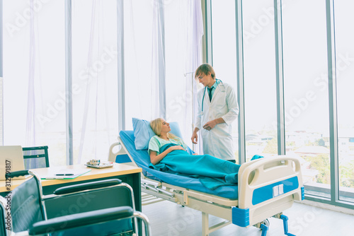 Asian young male doctor being injecting a young woman patient, who shows anxious facial expression and lying in bed In the room to treat the illness better.