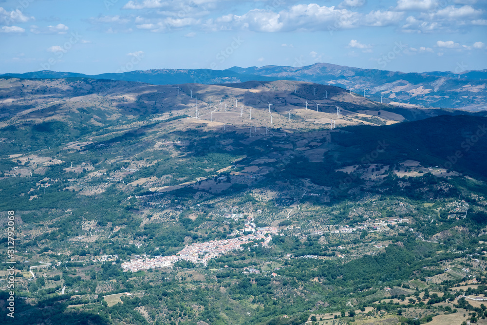 aerial of Montemurro village and wind farm on hill from east, Italy