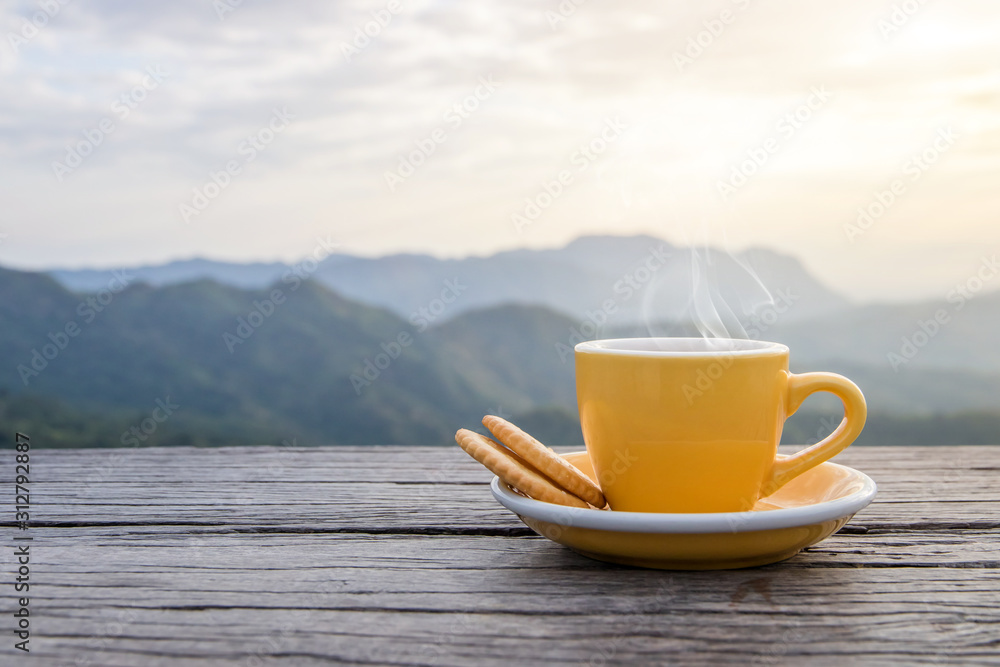 A white cup of hot espresso coffee mugs placed with cookies on a wooden floor with morning fog and moutains with sunlight background,coffee morning