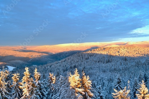 Krkonose Mountains in winter, Czech Republic. Frozen trees, the highest peak Snezka in the background. Ridge covered with snow, sunset. View from the look out tower Stepanka. photo