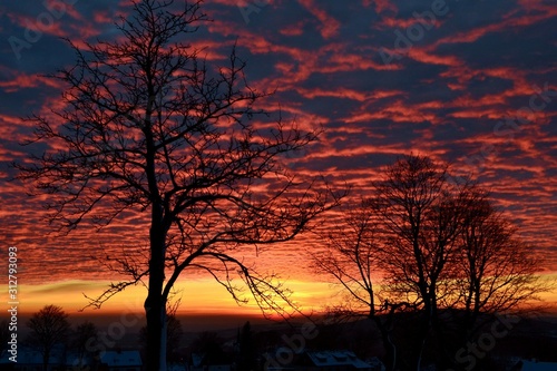 Beautiful winter sunset in Krkonose Mountains. Frozen trees  silhouettes of mountains  clouds  smoking church in the valley.