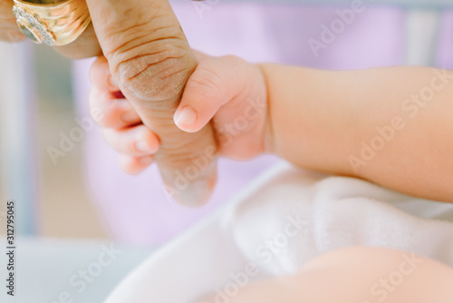 Newborn Baby is holding fingers of his grandmother - happy family moments