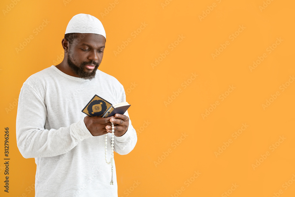 African-American Muslim man with Koran and beads on color background African-American Muslim man with Koran and beads on color background