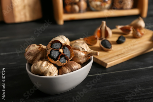 Bowl with black garlic on kitchen table photo