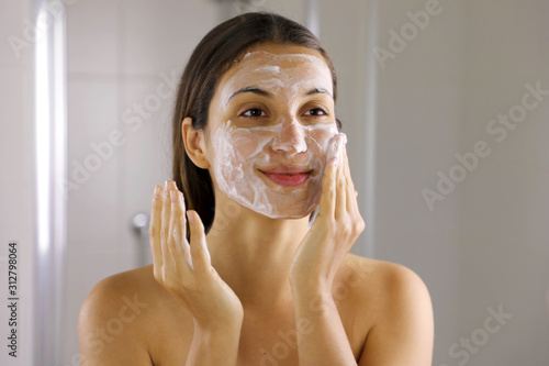 Skincare woman washing face  foaming soap scrubbing skin. Face wash exfoliation scrub soap woman washing scrubbing with skincare cleansing product. Enjoying relaxing time.