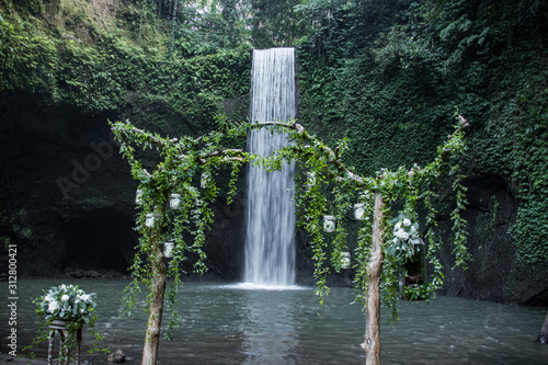 Wedding Arbor and Perfect Bridal Veil Waterfall In The Middle Of A Thick Green Forest. Tibumana Waterfall in Ubud, Bali, Indonesia photo