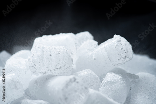 Dry ice cubes with vapor on black background.