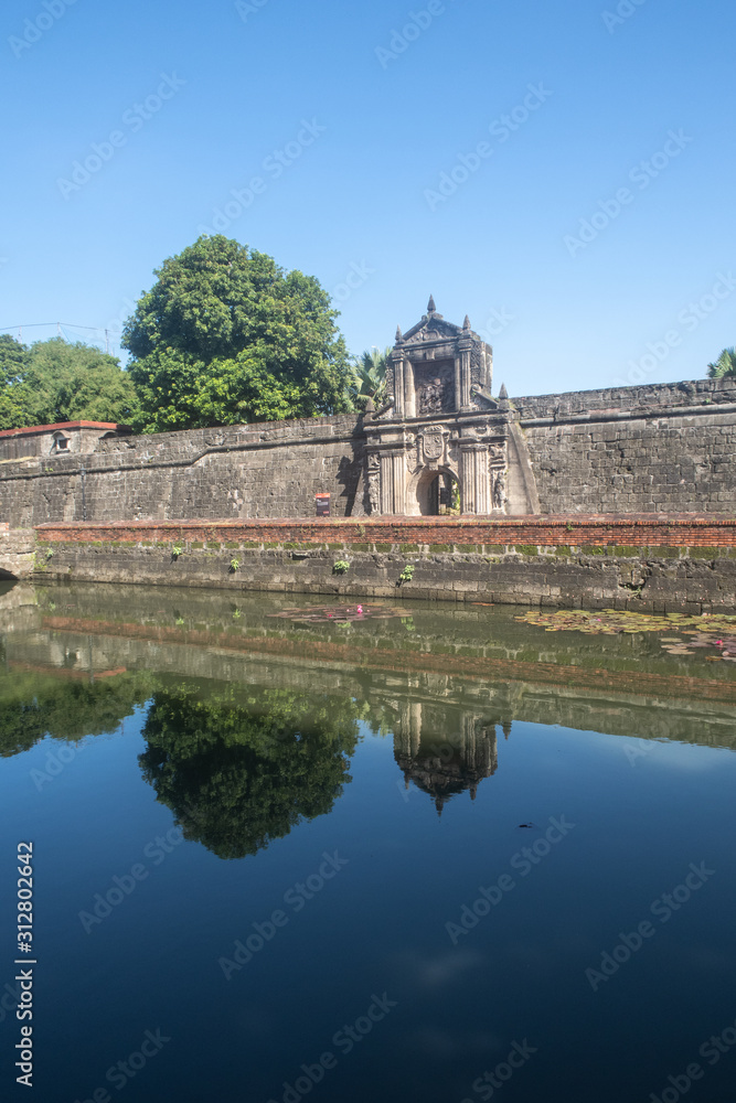 Fort Santiago Entrance Archway With Still Moat River In Front and Spanish Stone Carving Design in Intramuros, Manila, Philippines