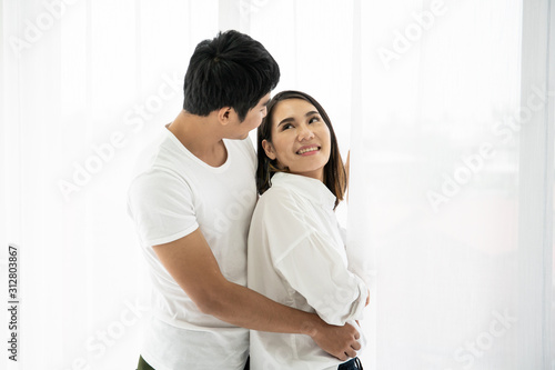Asian young couple's portrait, a couple standing and talking near the window in the morning.