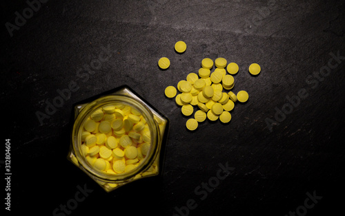 small round yellow pills in clear glass hexagonal jar