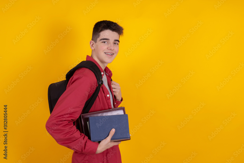 young man or teenage student isolated on color background with backpack and books