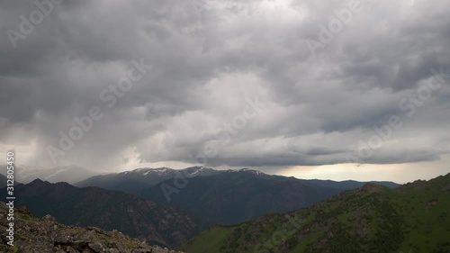 Panarama storm in time - dramatic rain clouds approaching the hill. A big mountain ridge under the thunderclouds. 4k footage.