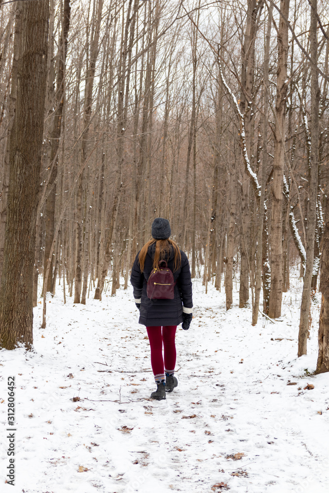Woman walking on snow covered trail in forest