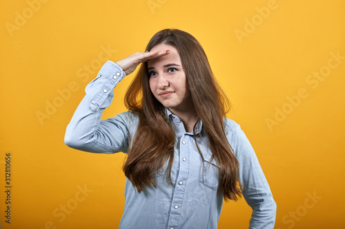 Caucasian lady wearing fashion shirt isolated on orange background in studio keeping palm on forehead, looking into distance. People emotions, lifestyle concept.