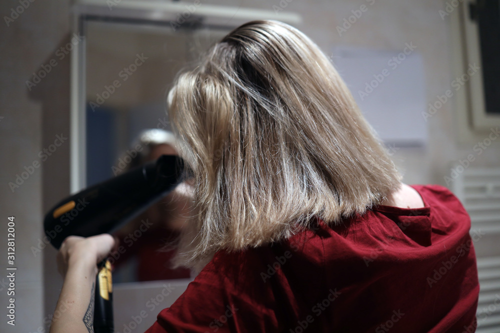 blonde girl dries wet hair with a hairdryer blonde girl dries wet hair with a hairdryer