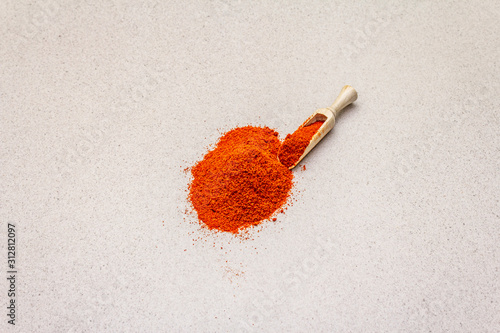 Magyar (Hungarian) brilliant red sweet paprika powder. Traditional ingredient for cooking healthy food. Wooden scoop, stone concrete background photo