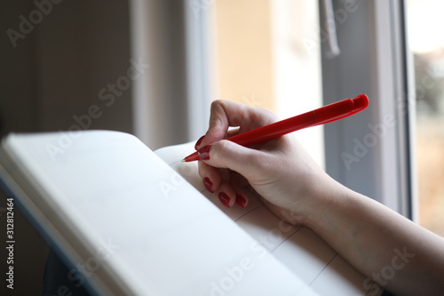 Female young hands write down goals or plans or tasks in a notebook 