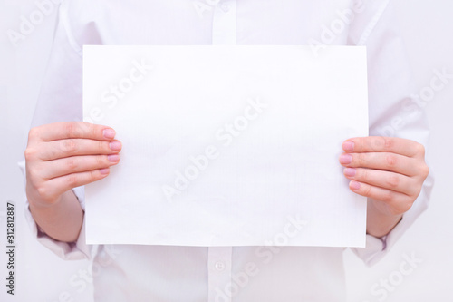 a white sheet of paper in the hands of a man in a white shirt. mockup. place for your text.
