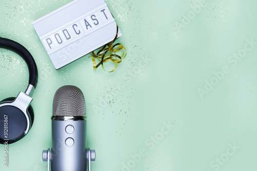 Top view photo of podcast concept - lightbox with letters podcast on it, headphones and professional microphone