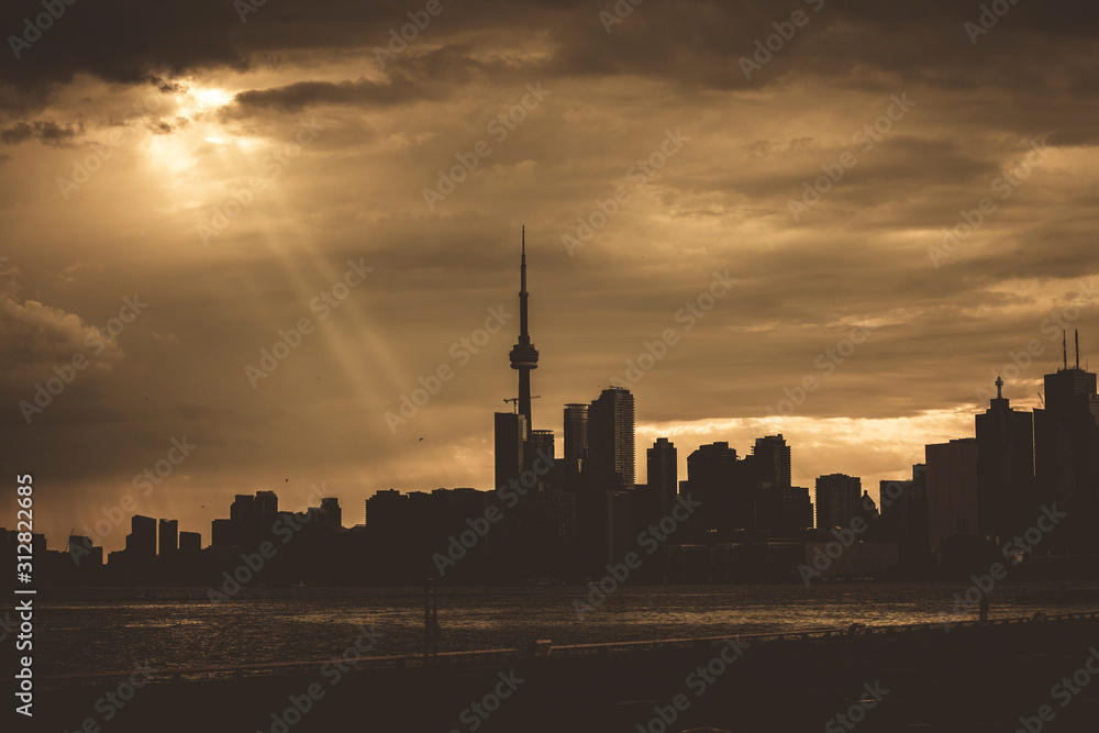 Naklejka premium A high-contrast view of the Toronto skyline with a dramatic sky covered in clouds, Toronto, Ontario, Canada