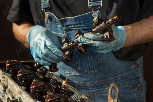 Dłonie mechanika samochodowego w rękawicach jednorazowych trzymają element silnika. Remont silnika, demontaż silnika samochodowego.
