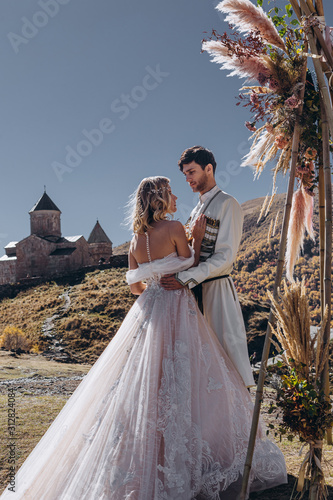 young, stylish, loving brides posing for a photo on an incredibly beautiful background of the Caucasus Mountains: hugging, kissing, laughing, and rejoicing in the happiest day of their lives