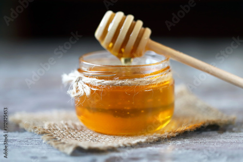 Selective focus. Jar of honey. Stick for honey.