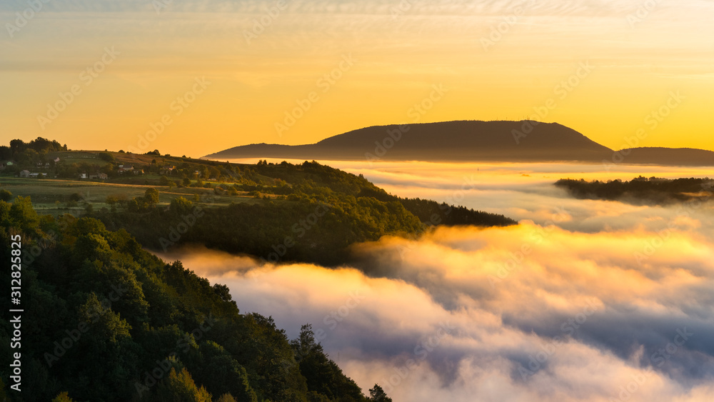 Cloud inversion above hills during colorful sunrise 