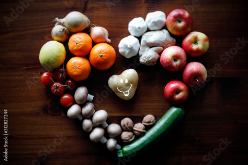 Herzförmige Kartoffel mit lachendem Gesicht, Obst und Gemüse aus biologischen Anbau.