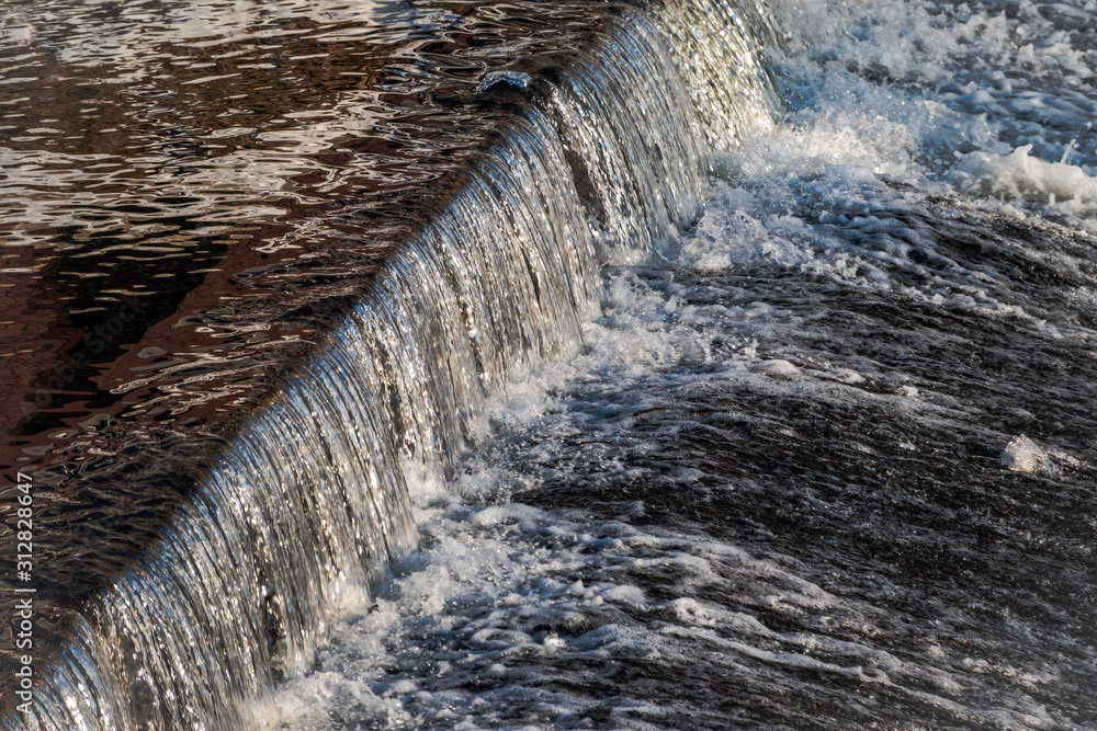 A small flat cascade in a calm river A small flat cascade in a calm river