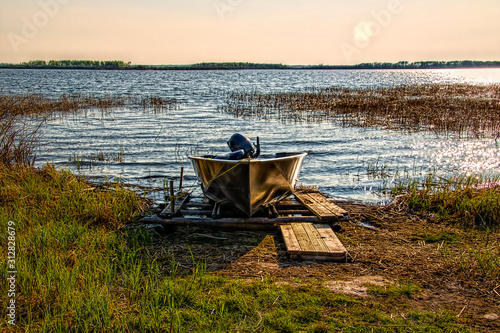 Small aluminum fishing board with an outboard motor run ashore on Lac Ile-a-la-Crosse Saskatchewan Canada