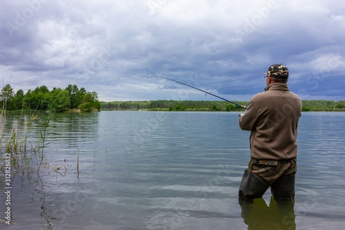 angler catching fish in lake during cloudy day