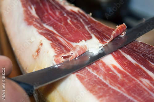 Traditional Spanish food jamon Serrano, cutting with a special long knife