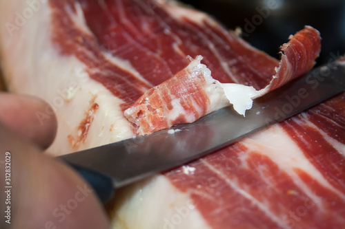 Traditional Spanish food jamon Serrano, cutting with a special long knife