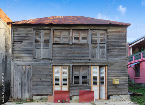 Typical wooden and rusted house in Martinique, French West Indies. Tropical multicolor windows