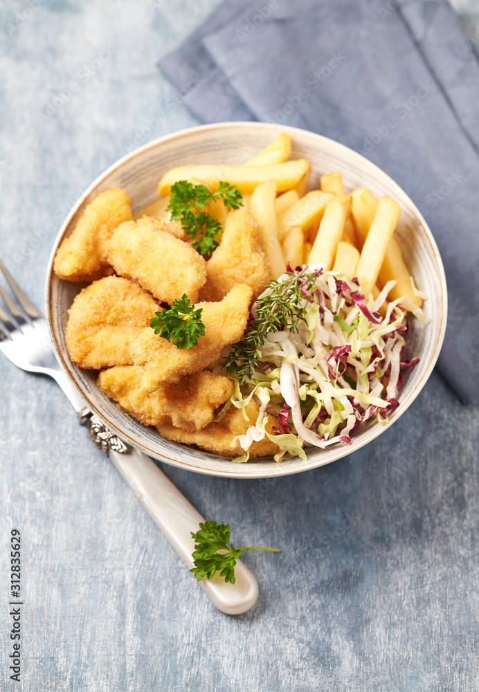 Chicken nuggets with raw salad and french fries on bright wooden background. Chicken nuggets with raw salad and french fries on bright wooden background.
