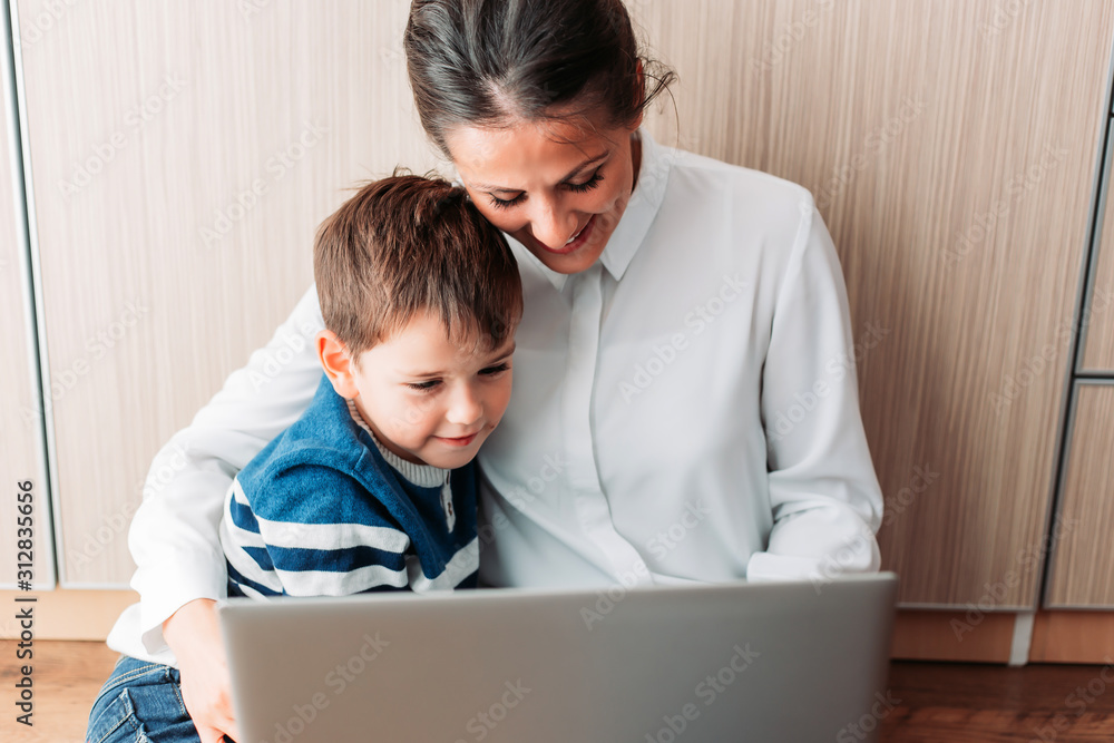 Beautiful young mom and her son, sitting on the floor looking at laptop. Beautiful young mom and her son, sitting on the floor looking at laptop.